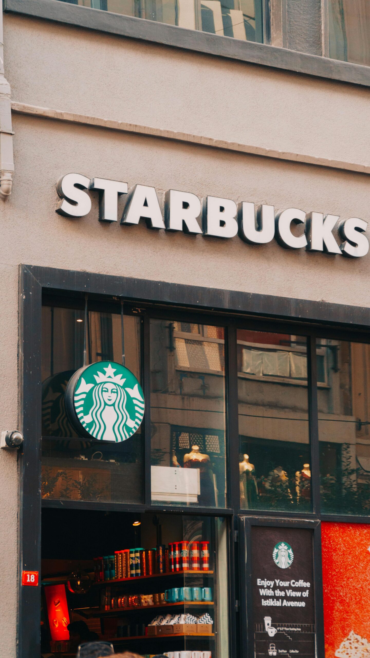 View of a Starbucks coffee shop with glass windows and signage in a bustling street.